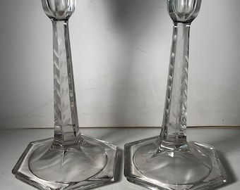 May include: A pair of clear glass candle holders with a hexagonal base and etched leaf designs. The candle holders are approximately 25 cm tall.