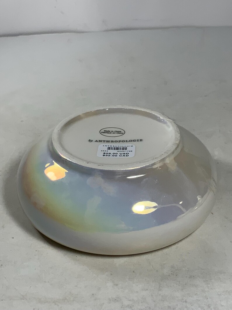 Może przedstawiać: Biała ceramiczna miska z iryzującym wykończeniem. Miska ma etykietę z napisem "by Anthropologie" i podaje cenę 29,00 USD i 32,00 CAD.
