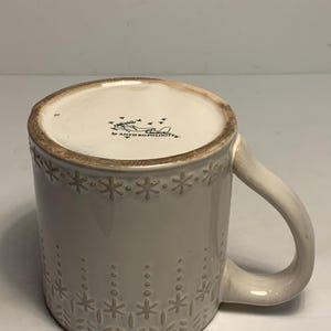 Peut inclure: Une tasse en c&eacute;ramique cr&egrave;me avec un motif d&eacute;coratif de flocons de neige et de points. La tasse a une anse incurv&eacute;e et le texte "ANTHROPOLOGIE" est visible en bas.