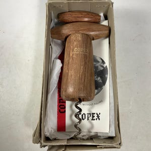 May include: A wooden corkscrew with a metal worm in a box. The corkscrew is made by COPEX and says "Made in England" on the side. The box has a white paper insert with the text "COPEX WITHOUT PULLING" on it.