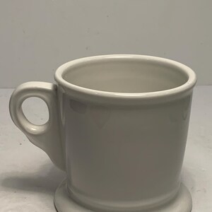 Puede incluir: Una taza de cer&aacute;mica blanca con un asa redondeada y una base circular ancha. La taza tiene un dise&ntilde;o simple y cl&aacute;sico y un acabado brillante. La taza es adecuada para bebidas calientes.