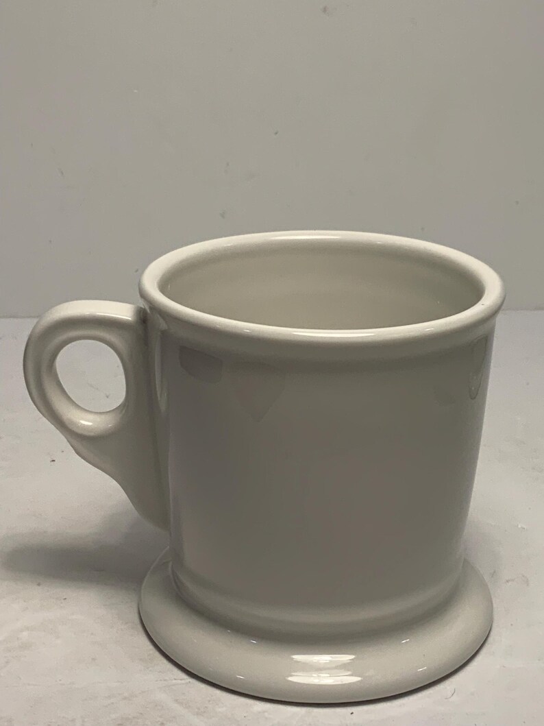 Puede incluir: Una taza de cer&aacute;mica blanca con un asa redondeada y una base circular ancha. La taza tiene un dise&ntilde;o simple y cl&aacute;sico y un acabado brillante. La taza es adecuada para bebidas calientes.