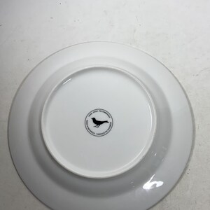May include: White ceramic plate with a black bird logo on the bottom. The logo says "Hand Wash Recommended" and "Made in Indonesia - Fabriqu&eacute; en Indon&eacute;sie".