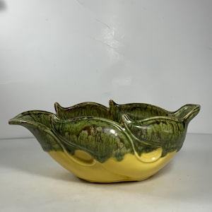 May include: A yellow ceramic bowl with green leaf-shaped edges. The bowl has a mottled green glaze with brown accents.