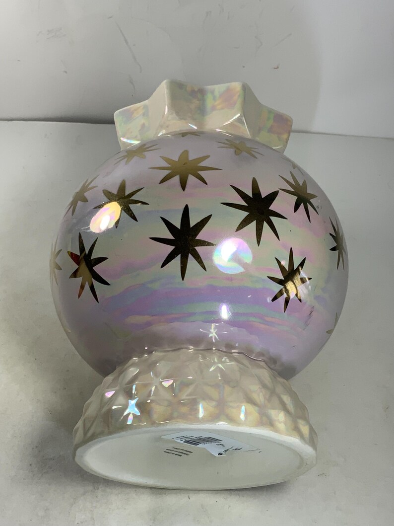May include: Iridescent decorative orb-shaped vase with gold star accents. The vase has a ruffled top and a textured base. The pearlescent finish reflects light, creating a shimmering effect. A unique home decor item.