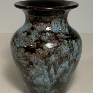 May include: A ceramic vase with a flared rim and a rounded body, featuring a glossy glaze with a mottled pattern of deep dark brown and light blue colours that blend together in a fluid, drip-like effect across the entire exterior surface.