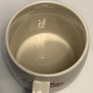 Puede incluir: Taza de cer&aacute;mica de color crema con forma redondeada y asa. El interior es de color beige claro y el exterior presenta un sutil estampado floral en rosa y verde. La taza tiene un dise&ntilde;o sencillo y cl&aacute;sico.