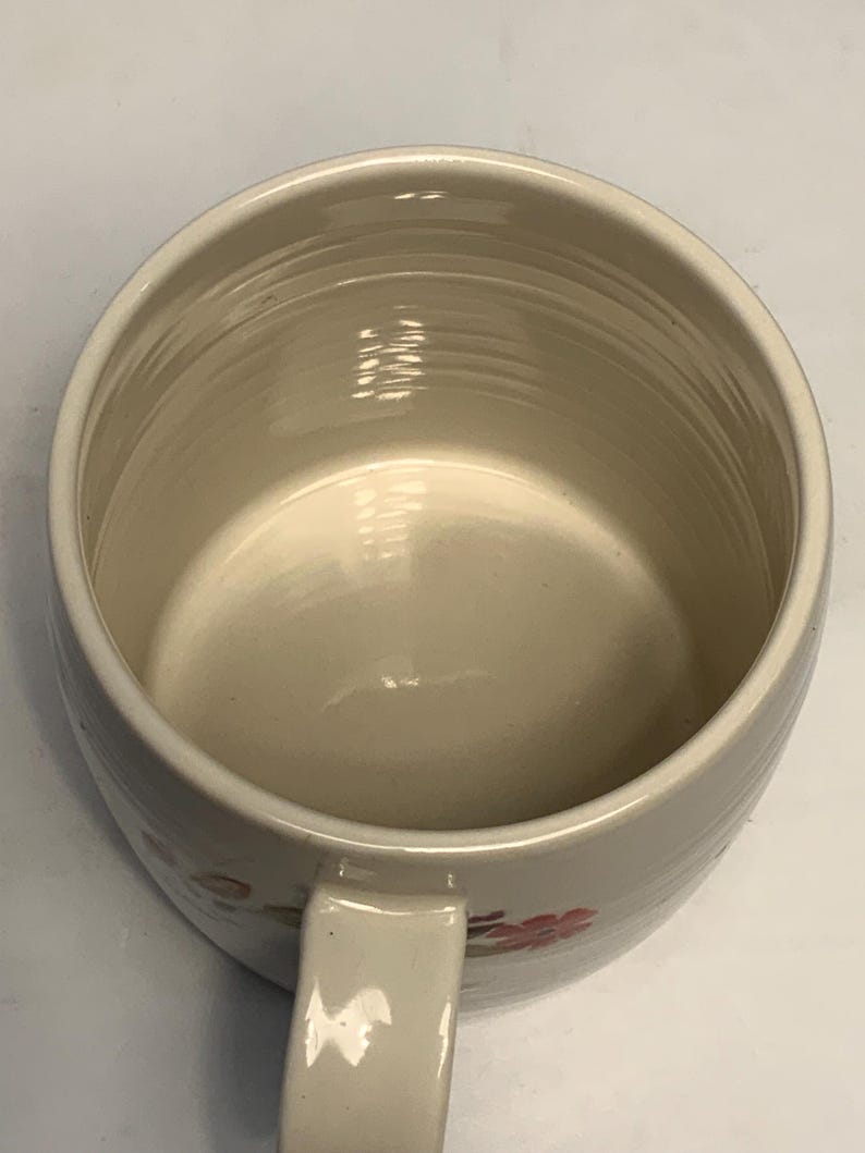 Puede incluir: Taza de cer&aacute;mica de color crema con forma redondeada y asa. El interior es de color beige claro y el exterior presenta un sutil estampado floral en rosa y verde. La taza tiene un dise&ntilde;o sencillo y cl&aacute;sico.