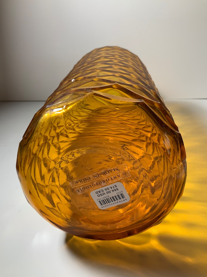 May include: Amber glass vase with a textured, geometric pattern. The vase is labelled "Anthropologie" and "Made in India" with a price tag of &pound;24.00.