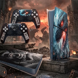 Könnte beinhalten: Eine Spielkonsole und Controller mit Godzilla- und King-Kong-Grafiken. Die Controller sind schwarz mit roten und weißen Akzenten, und die Konsole hat ein blaues und rotes Godzilla-Design. Der Hintergrund zeigt eine zerstörte Stadt.