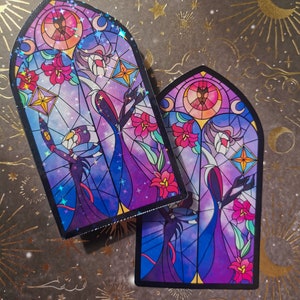 May include: Two stained glass stickers featuring a purple and blue background with a black silhouette of two figures in long robes. The figures are surrounded by pink flowers and stars. The stickers are in the shape of a gothic arch.