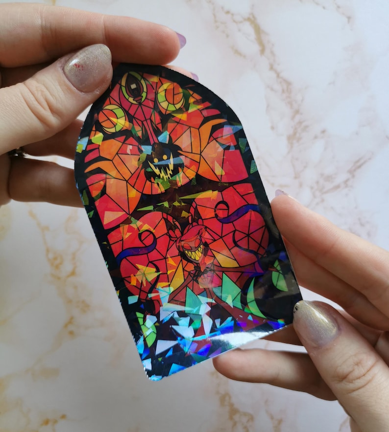 Puede incluir: Una pegatina de vitral con un dise&ntilde;o rojo, naranja y amarillo. La pegatina presenta una silueta negra de una criatura con dientes y garras afiladas. La pegatina tiene un acabado hologr&aacute;fico.