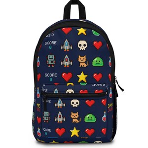 May include: A navy blue backpack featuring a repeating pixel art pattern of spaceships, skulls, red hearts, yellow stars, green slimes, robots, cats, and potion bottles. The design includes text elements reading SCORE 0, LIVES 0, and GAME OVER.