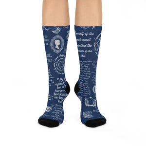 May include: A pair of navy blue crew socks featuring a white printed pattern of literary quotes, silhouettes, and vintage-style illustrations. The text includes phrases like One half of the world cannot understand the pleasures of the other.