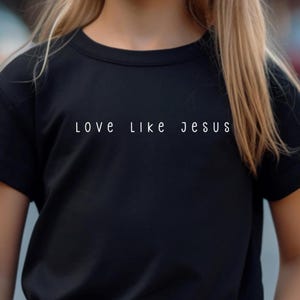 May include: Black crew neck t-shirt with the white text "LOVE LIKE JESUS" across the chest. The shirt is made of a soft material and is suitable for everyday wear.