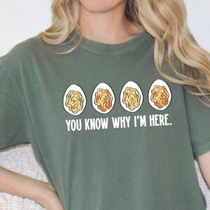 May include: A green t-shirt with a graphic of four deviled eggs and the text "You know why I'm here."