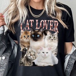 May include: Black t-shirt with the text "CAT LOVER" in pink glitter letters. The shirt features a graphic of five cats in various poses.