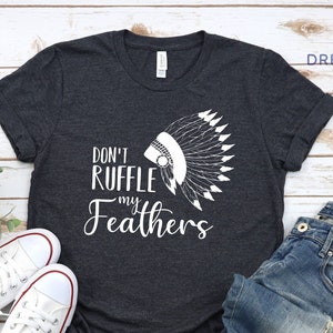 May include: A dark gray heather t-shirt with a white graphic of a Native American headdress and the text "Don't ruffle my feathers".