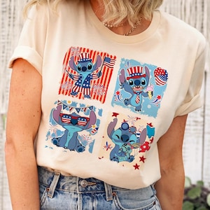 May include: Cream-colored t-shirt featuring a four-panel design of the character Stitch in patriotic attire. Each panel showcases Stitch with American flag elements, fireworks, and ice cream, celebrating Independence Day.