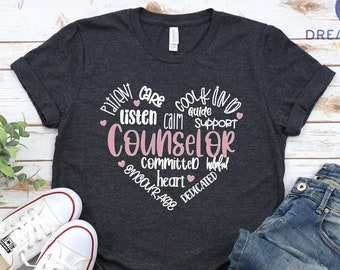 May include: Dark heather grey t-shirt with a pink heart design that says "Patient care cool & kind listen calm guide support Counselor committed heart encourage dedicated".