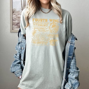 May include: A light green t-shirt with a gold graphic print that reads "Fourth Wing" and includes a dragon and other imagery. The text on the shirt reads "There's nowhere in existence you could go that I wouldn't find you...Violence. A dragon without its rider is a tracer. A rider without their dragon is a ghost. I am infinite. I am completely utterly obsessed with you."