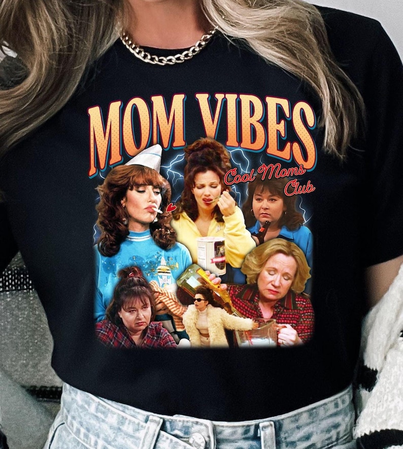 Puede incluir: Camiseta negra con un estampado gr&aacute;fico de un grupo de mujeres con el texto "Mom Vibes Cool Moms Club".