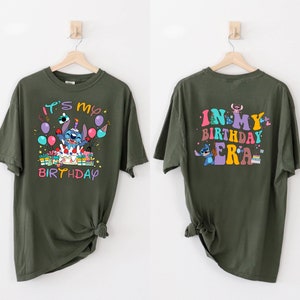 Puede incluir: Dos camisetas verdes con un personaje azul Stitch. La camiseta delantera dice "Es mi cumplea&ntilde;os" y la camiseta trasera dice "En mi era de cumplea&ntilde;os".