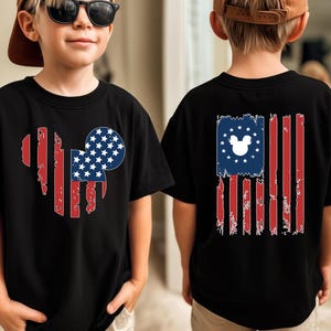 May include: Black t-shirts with a patriotic design. The front features a heart-shaped American flag with a Mickey Mouse head. The back displays a distressed American flag with a Mickey Mouse head in the stars.