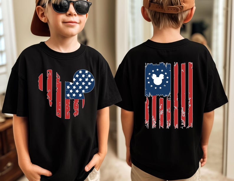 May include: Black t-shirts with a patriotic design. The front features a heart-shaped American flag with a Mickey Mouse head. The back displays a distressed American flag with a Mickey Mouse head in the stars.