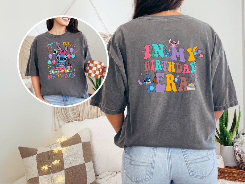 Puede incluir: Una camiseta gris con un personaje de dibujos animados azul que sostiene una guitarra y el texto "In My Birthday Era". La parte delantera de la camiseta tiene una versi&oacute;n m&aacute;s peque&ntilde;a del personaje con el texto "It's My Birthday".