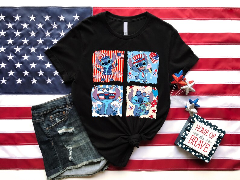 May include: Black t-shirt featuring four panels with a cartoon character in patriotic attire. The character is blue with large ears and is wearing sunglasses, a hat, and holding a flag. The shirt is displayed with denim shorts and an American flag.