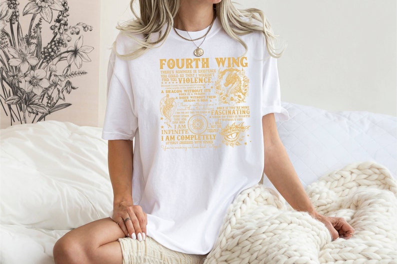 May include: White t-shirt with a gold graphic print that reads "Fourth Wing" and includes a dragon illustration. The text includes the phrases "There's nowhere in existence you could go that I wouldn't find you", "I am infinite", and "I am completely utterly obsessed with you".