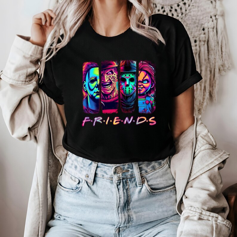 May include: Black t-shirt featuring a colorful graphic of four horror movie characters. The word "F.R.I.E.N.D.S" is printed in a rainbow font below the characters. The shirt is a crew neck style.