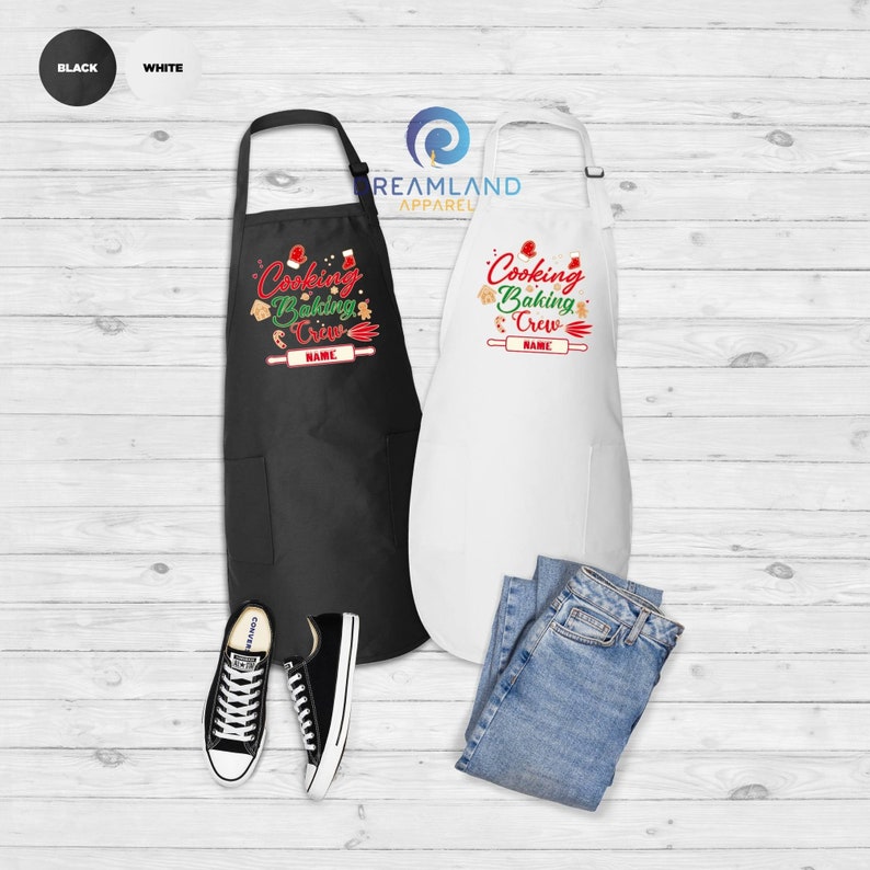 May include: Two Christmas-themed aprons, one black and one white, with the text "Cooking Baking Crew" and a space for a name. The aprons are displayed on a woodgrain surface with a pair of black sneakers and blue jeans.