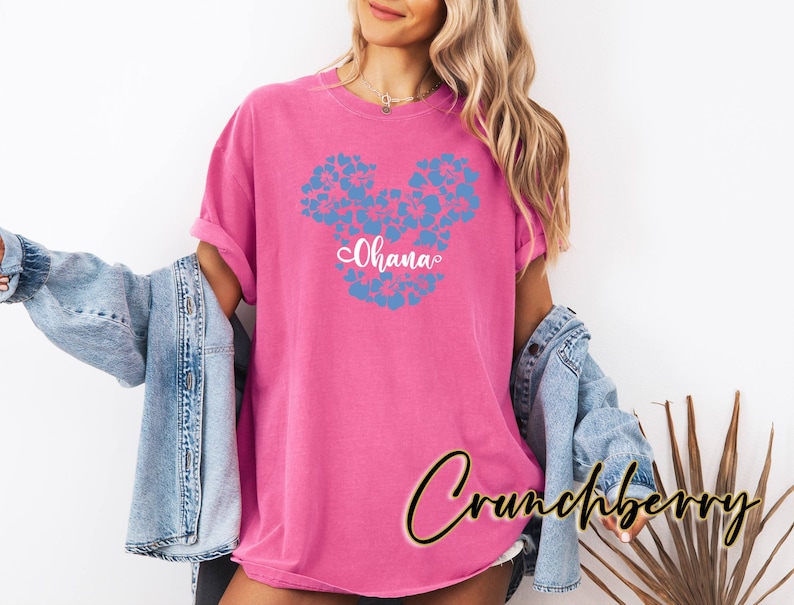 Puede incluir: Camiseta rosa con un dise&ntilde;o de Mickey Mouse floral azul y la palabra "Ohana" en letras blancas.