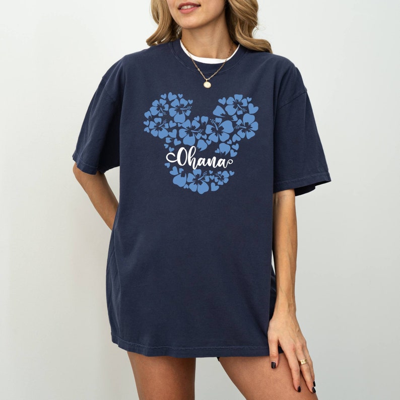 Puede incluir: Una camiseta azul marino con un dise&ntilde;o de Mickey Mouse floral azul y la palabra "Ohana" en letras blancas.