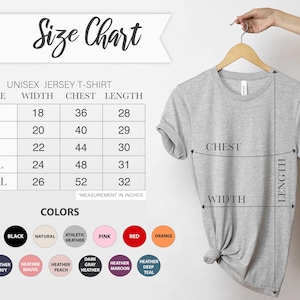 May include: A light gray unisex jersey t-shirt hanging on a wooden hanger. The image includes a size chart with measurements in inches for width, chest, and length, and a color chart with various options.