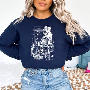 May include: Navy blue sweatshirt featuring a white graphic of Star Wars characters and elements, including Darth Vader, Boba Fett, and the Star Wars logo. The design is a detailed illustration of the iconic characters and spacecraft from the film series.