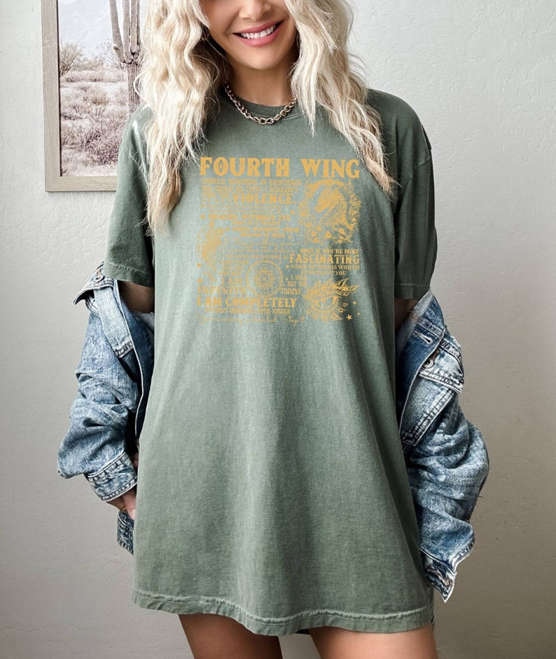 May include: A green oversized t-shirt with a vintage-style graphic design that reads "Fourth Wing" and includes a detailed illustration of a dragon. The text is in a gold color.