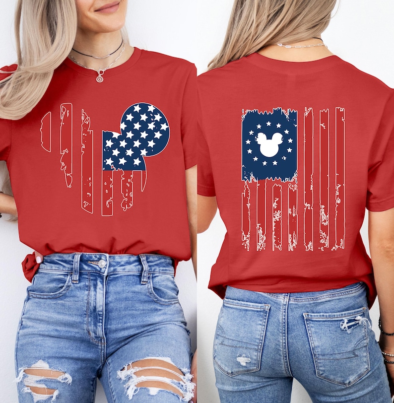 May include: Red t-shirt featuring a distressed American flag design with a Mickey Mouse head silhouette. The front design has a flag-inspired shape with stars and stripes. The back of the shirt also has a flag design with a Mickey Mouse head silhouette.