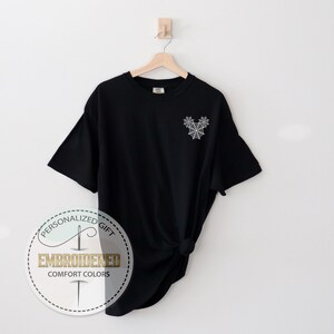 Pu&ograve; includere: T-shirt nero con un disegno a ragnatela ricamata bianca sulla parte superiore sinistra del petto. La maglietta &egrave; del marchio Comfort Colors. L'immagine include anche un logo circolare con le parole "Personalized Gift" e "Embroidered Comfort Colors".