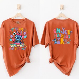 Puede incluir: Camiseta naranja con un personaje de dibujos animados de Stitch sosteniendo un pastel de cumplea&ntilde;os y globos. El texto "It's my birthday" est&aacute; impreso en la parte delantera de la camiseta. La parte posterior de la camiseta tiene el texto "In my birthday era" con un personaje de Stitch sosteniendo un pastel.