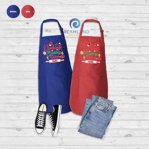 Może przedstawiać: Dwa świąteczne fartuchy, jeden w kolorze kr&oacute;lewskim, a drugi czerwony, z napisem "Cooking Baking Crew" i miejscem na imię. Fartuchy mają kieszeń z przodu.