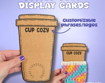 Op de afbeelding: Twee bruine papieren displaykaarten voor bekerhouders met zwarte omlijningen en tekst. De grotere kaart toont CUP COZY en CRAFTYBAKERDESIGNS. De kleinere kaart bevat een veelkleurige gehaakte bekerhouder. Tekst: COFFEE COZY DISPLAY CARDS.