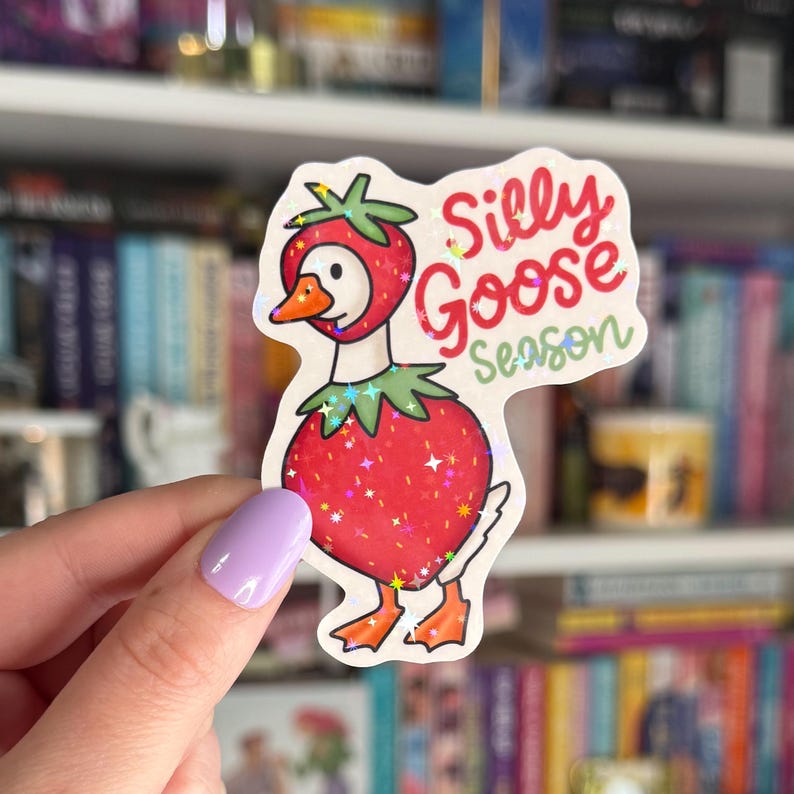 Op de afbeelding: Een sticker met een cartoon-gans die een aardbeikostuum draagt. De sticker heeft een holografische afwerking en zegt "Silly Goose Season".