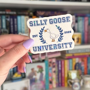 Op de afbeelding: Een witte sticker met een blauwe rand en glitter. De sticker zegt "Silly Goose University" met een afbeelding van een gans en de tekst "Est 2025".