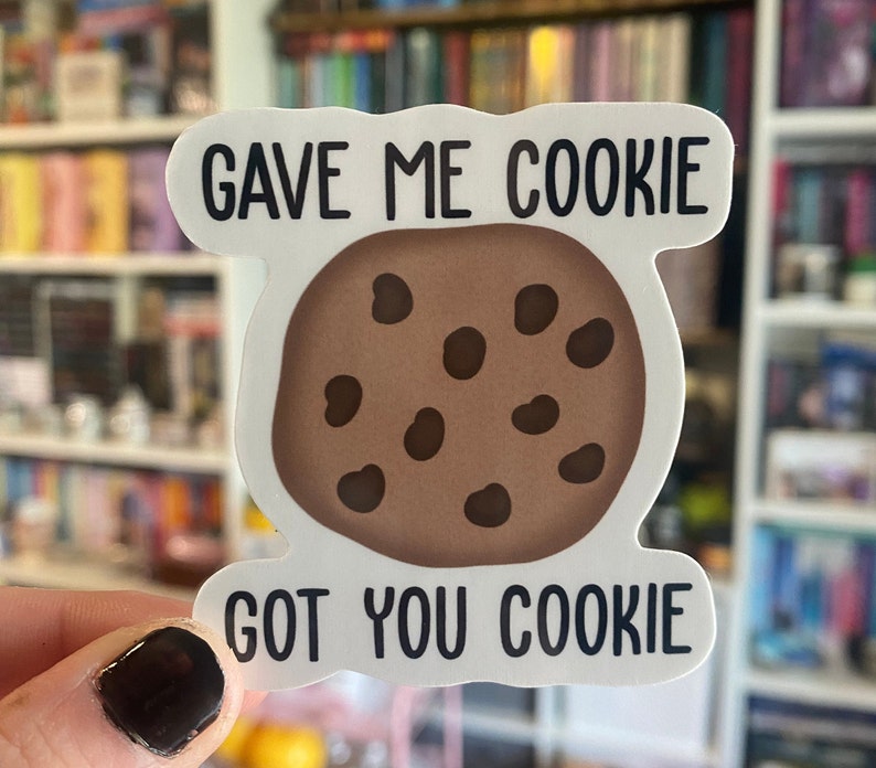 以下が含まれることがあります： 「Gave me cookie got you cookie」というテキストと、茶色のチョコレートチップクッキーのイラストが描かれた白いステッカーです。