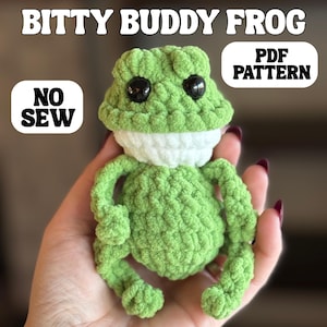 May include: A crocheted green frog with black eyes and a white neck, labeled "Bitty Buddy Frog." The image also includes the text "PDF PATTERN" and "NO SEW."
