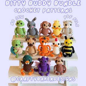 Op de afbeelding: Een verzameling van dertien kleine gehaakte dierenfiguren op een witte standaard met drie niveaus. De tekst luidt: BITTY BUDDY BUNDLE CROCHET PATTERNS NO SEW PDF FILE @CRAFTYBAKERDESIGNS. De figuren omvatten een kikker, konijn, aap, kuiken, kat, schildpad, hond, tijger, kip, bij, eend, draak en een luiaard.