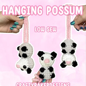 May include: Three crocheted possum plushies in white, gray, and black yarn with pink noses. Two are hanging from pink yarn loops, and one is held upright. Text reads HANGING POSSUM, LOW SEW, and CRAFTYBAKERDESIGNS in white with pink outlines.